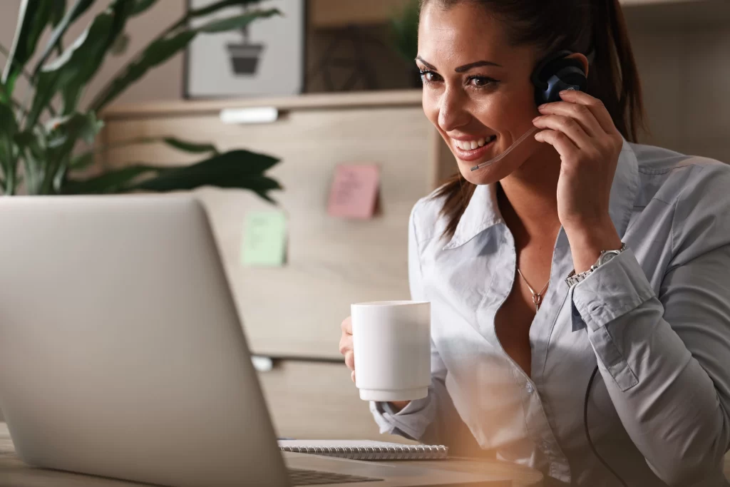 feliz-empresaria-tomando-cafe-enquanto-trabalhava-no-centro-de-atendimento-ao-cliente-e-conversando-